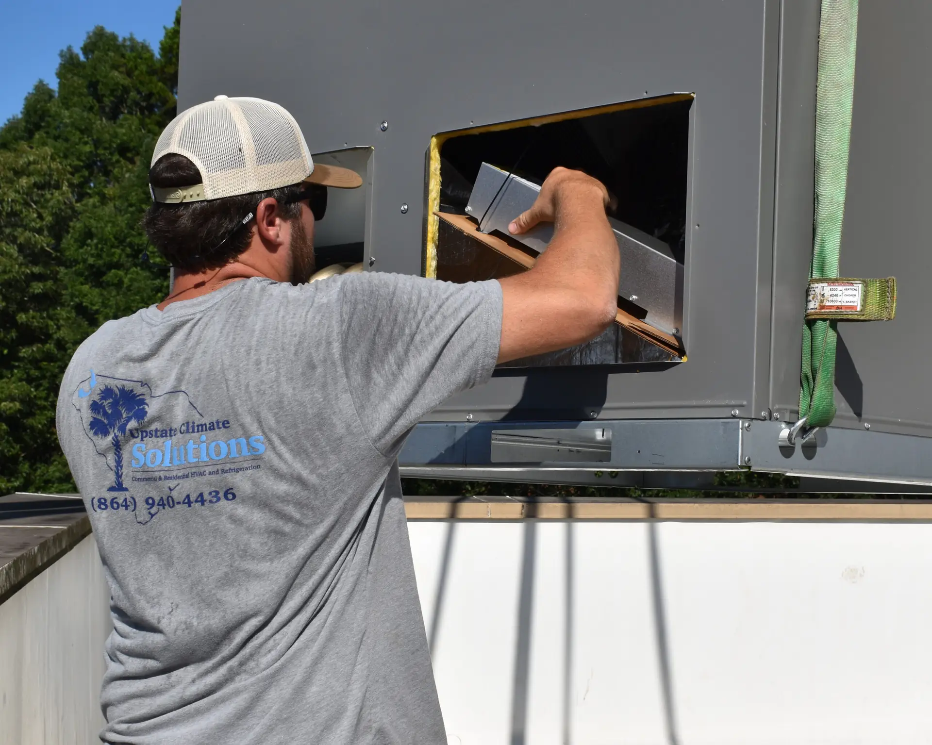 Upstate Climate Solutions employee working on HVAC system with a tshirt with logo on the back